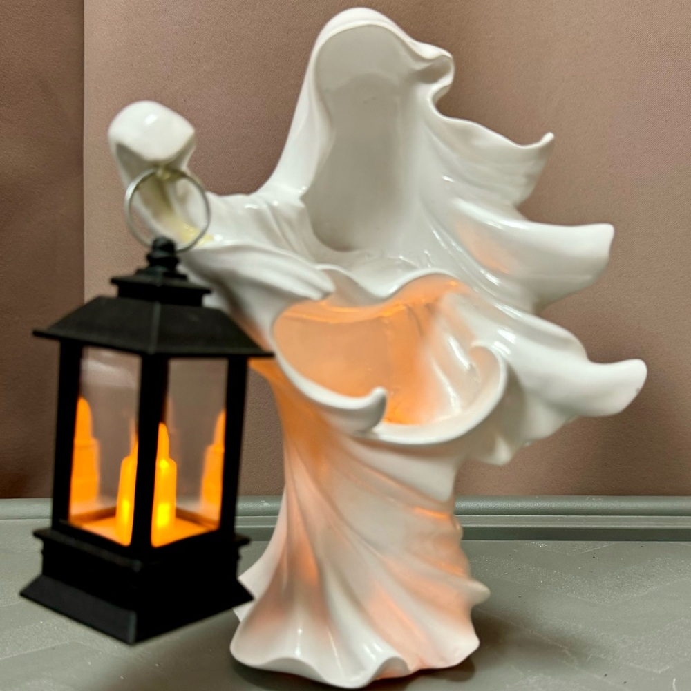 Miniature ghost holding lantern lights up